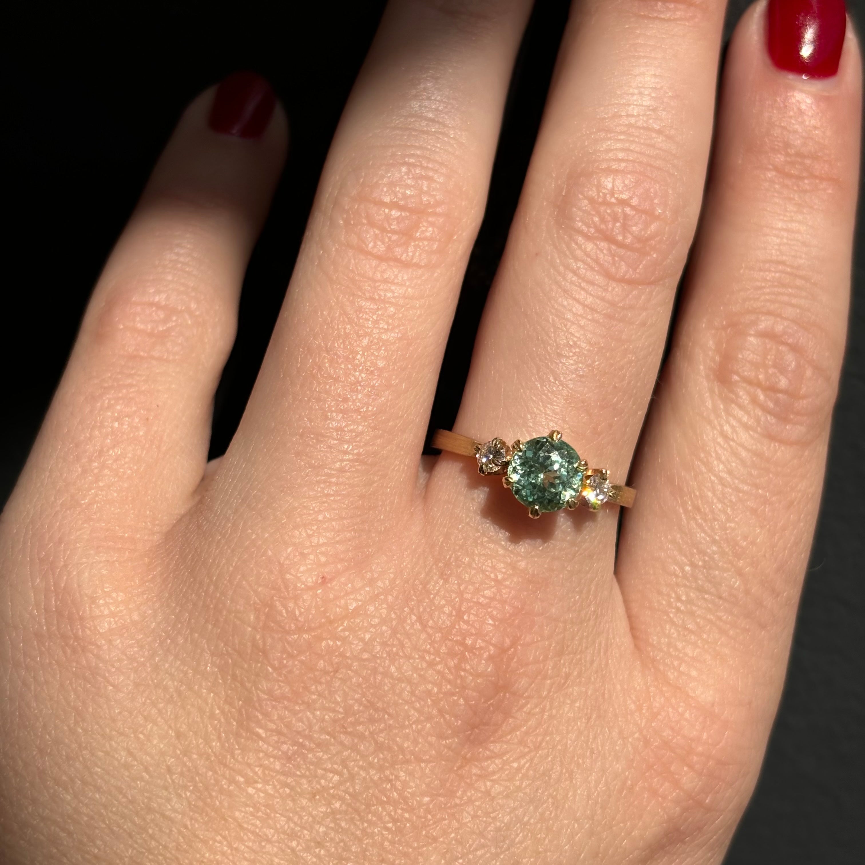 Seafoam sapphire engagement ring with diamond trillion side stones on a 14k yellow gold band featuring a six prong setting